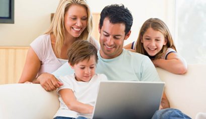 Family in living room with laptop smiling